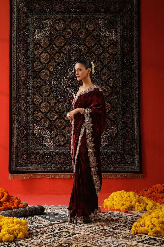 "Radiant Elegance: This deep maroon velvet saree, embellished with exquisite golden embroidery, exudes regality and charm, perfect for grand celebrations."